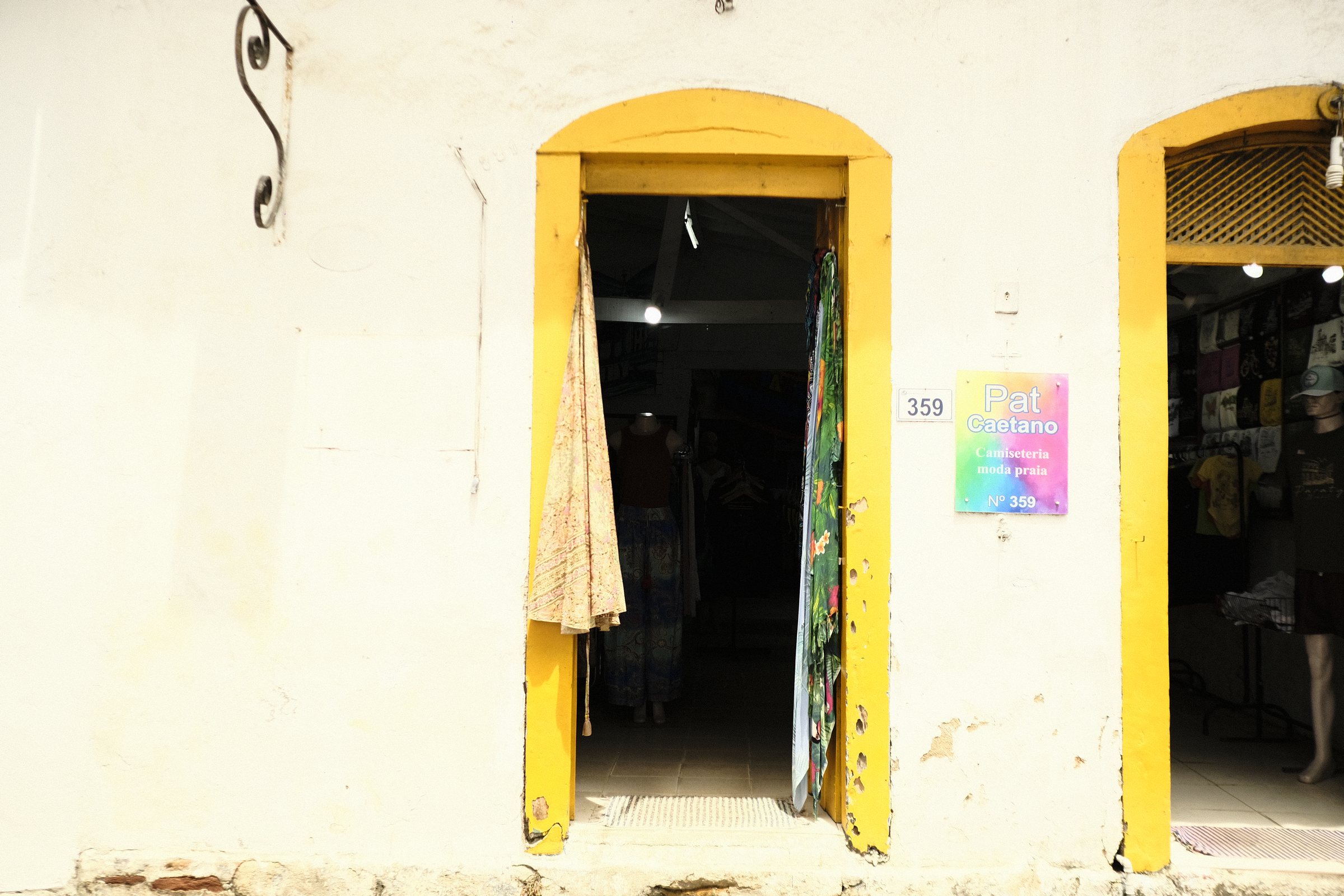 Yellow-framed doorway of a small clothing shop set in a white wall in Paraty